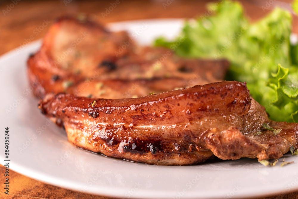 Homemade pork chop served with lettuce on a white plate. Homemade pork chop served with lettuce on a white plate.