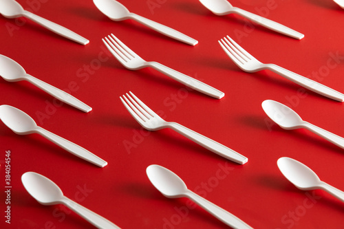 Disposable plastic cutlery forks and spoons with red background
