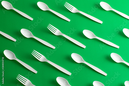 Disposable plastic cutlery forks and spoons forbidden Disposable plastic cutlery forks and spoons forbidden for pollution of the environment green background green background