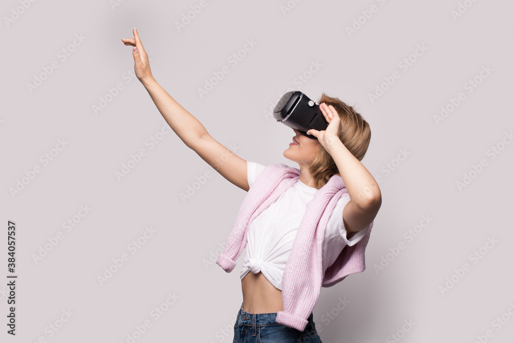 Blonde caucasian woman is touching something during a virtual reality experience with special headset on a white studio wall Blonde caucasian woman is touching something during a virtual reality experience with special headset on a white studio wall