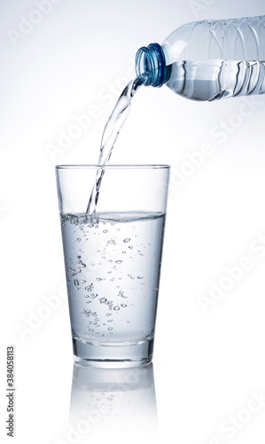 Pour water into a clear glass placed on a white background.