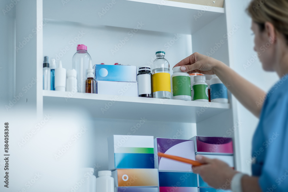Doctor in lab coat searching for a bottle with pills