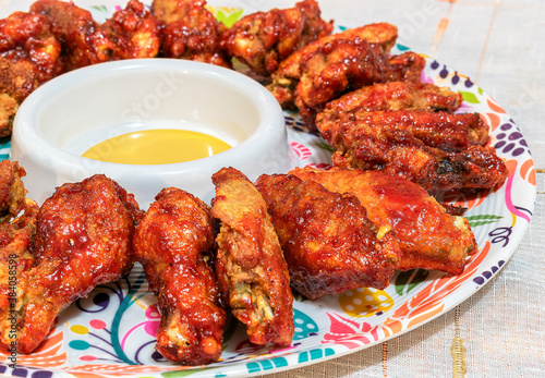 Homemade BBQ wings served in a colorful platter.