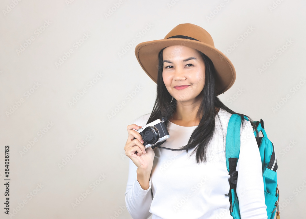 Portrait of Asian woman wearing white t-shirt and hat , holding camera and carrying backpack, smiling and looking at camera. Travelling concept. Portrait of Asian woman wearing white t-shirt and hat , holding camera and carrying backpack, smiling and looking at camera. Travelling concept.