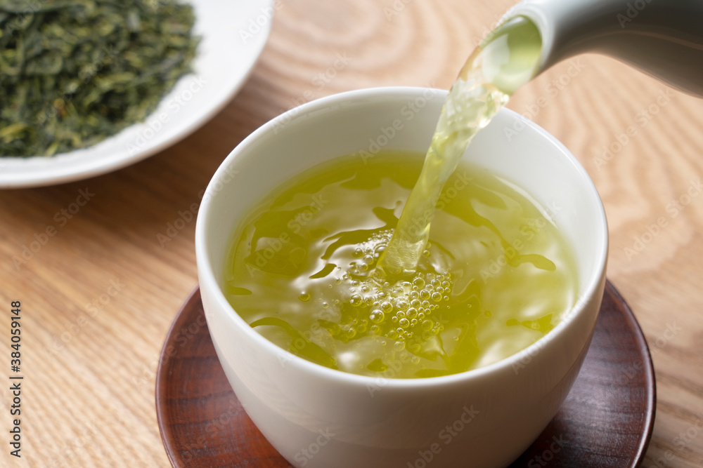 Pouring green tea into a teacup. Japanese green tea image Pouring green tea into a teacup. Japanese green tea image