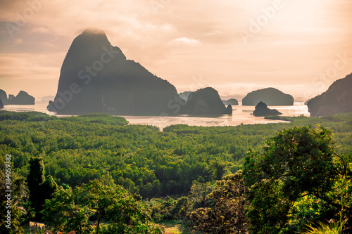 Natural background of seaside scenery  with coconut trees  boulders  sandy beach  and blurred sea waves.