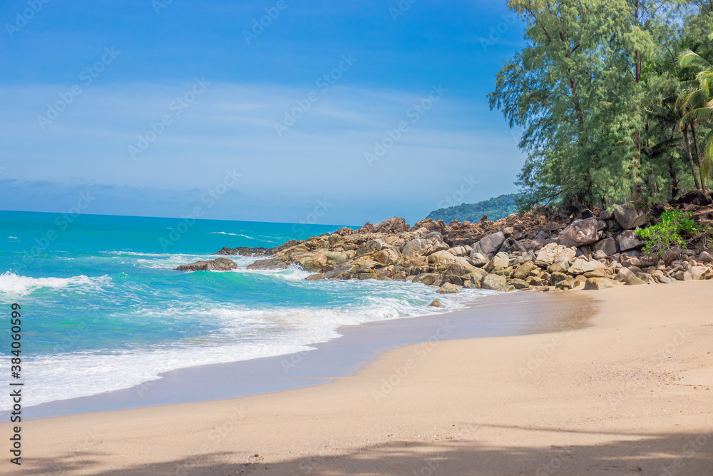 Natural background of seaside scenery (with coconut trees, boulders, sandy beach) and blurred sea waves.