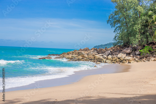 Natural background of seaside scenery (with coconut trees, boulders, sandy beach) and blurred sea waves.