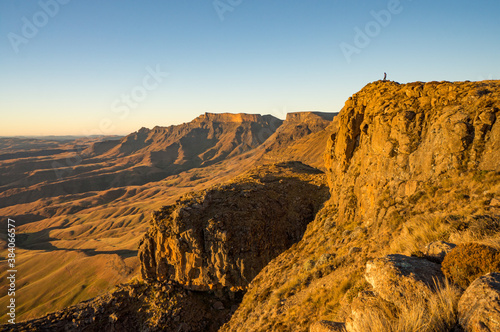 A hiker enjoys the breathtaking sunrise view from the high Drakensberg mountains of South Africa.