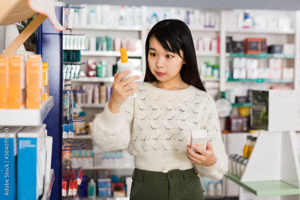Young chinese woman chooses antibacterial at the pharmacy. High quality photo