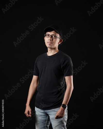 Young men in empty black T-shirts, stylish and posing like famous T-shirt models. Men's t-shirt template and mockup design for print. photo shoot models isolated black background. © AndhikaRaya