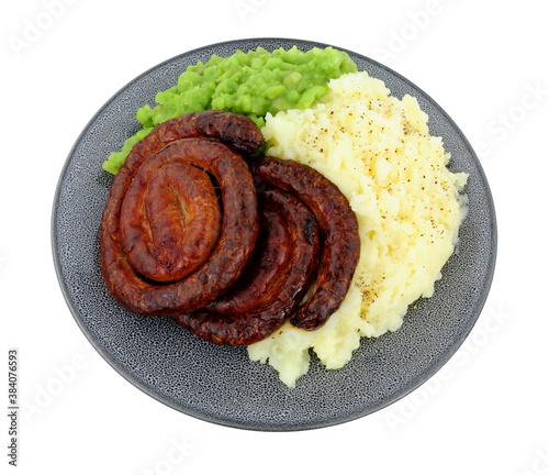 Cumberland pork sausage swirl and mashed potato meal with mushy peas isolated on a white background