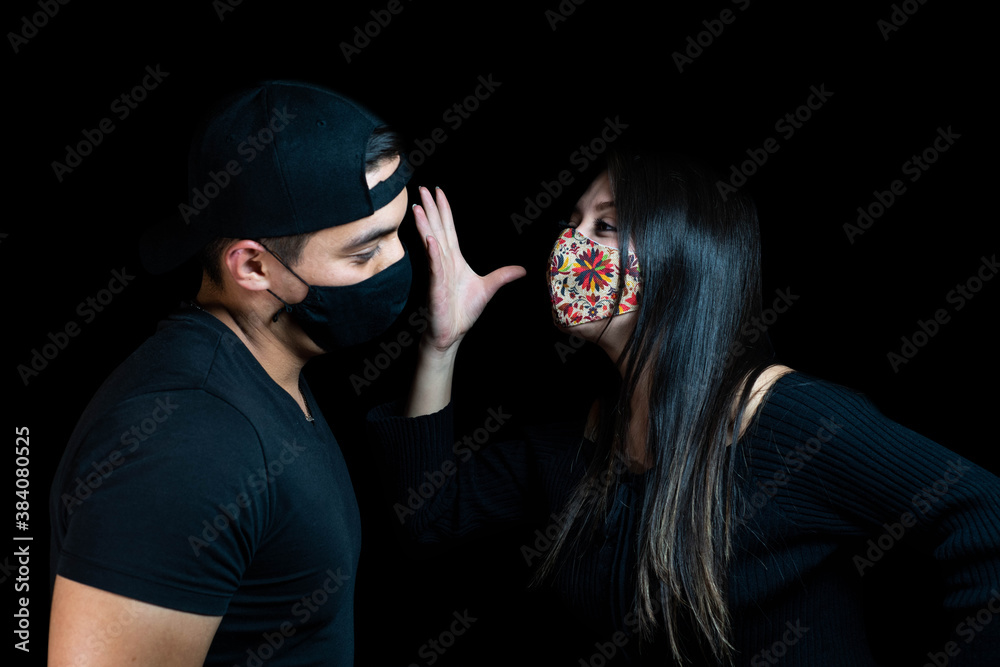 Man and woman arguing with mask on black background