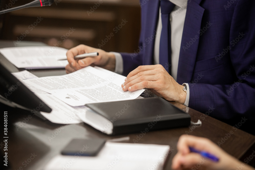 Fototapeta premium One of politician sitting by table with his hands over document during political summit or conference