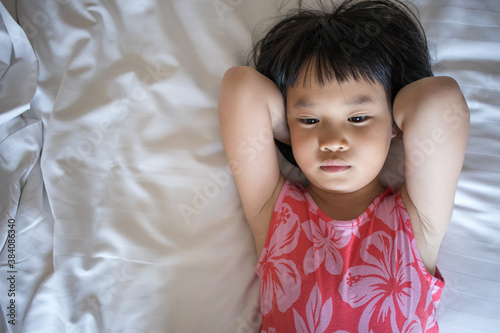 Chilled out Asian adorable child on white bed
