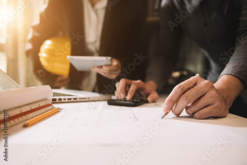 Businessman working as a team discussing data working and tablet, laptop with on on architectural project at construction site at desk in office.