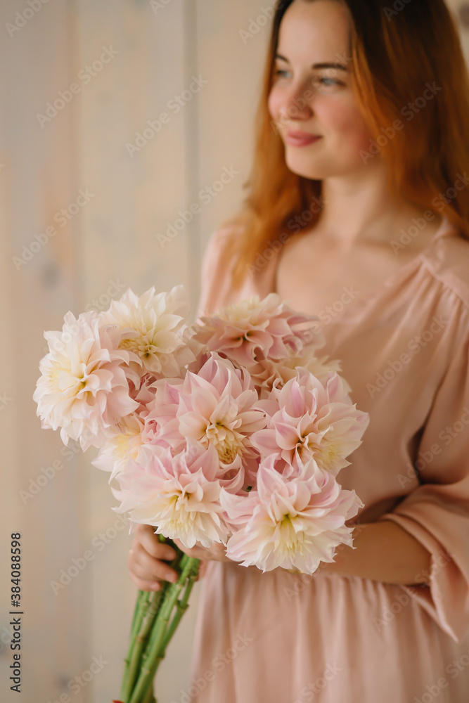 young woman florist in a pink dress with red hair holds a wedding bouquet of flowers roses