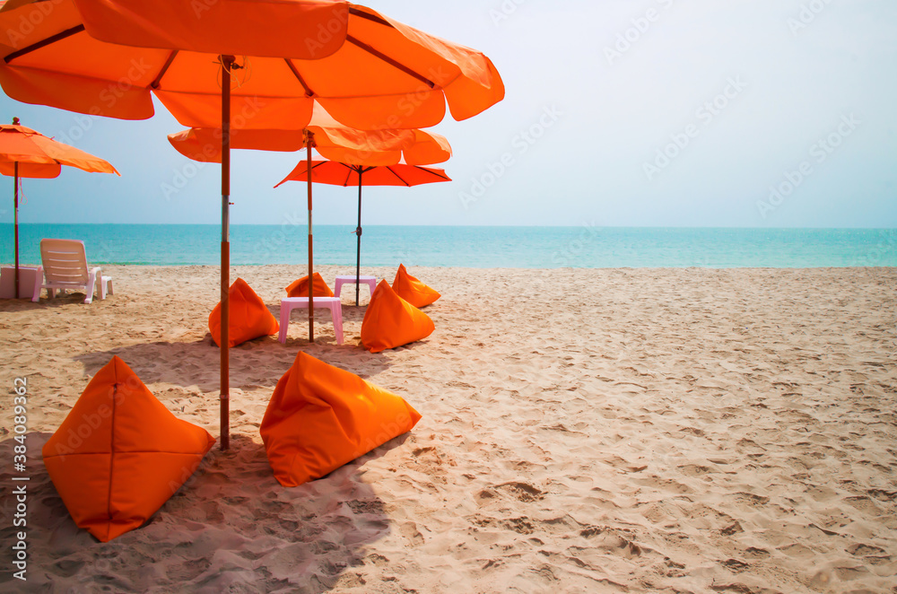 Orange umbrellas on white sandy beach along the beautiful sea in Cha Am, Thailand.