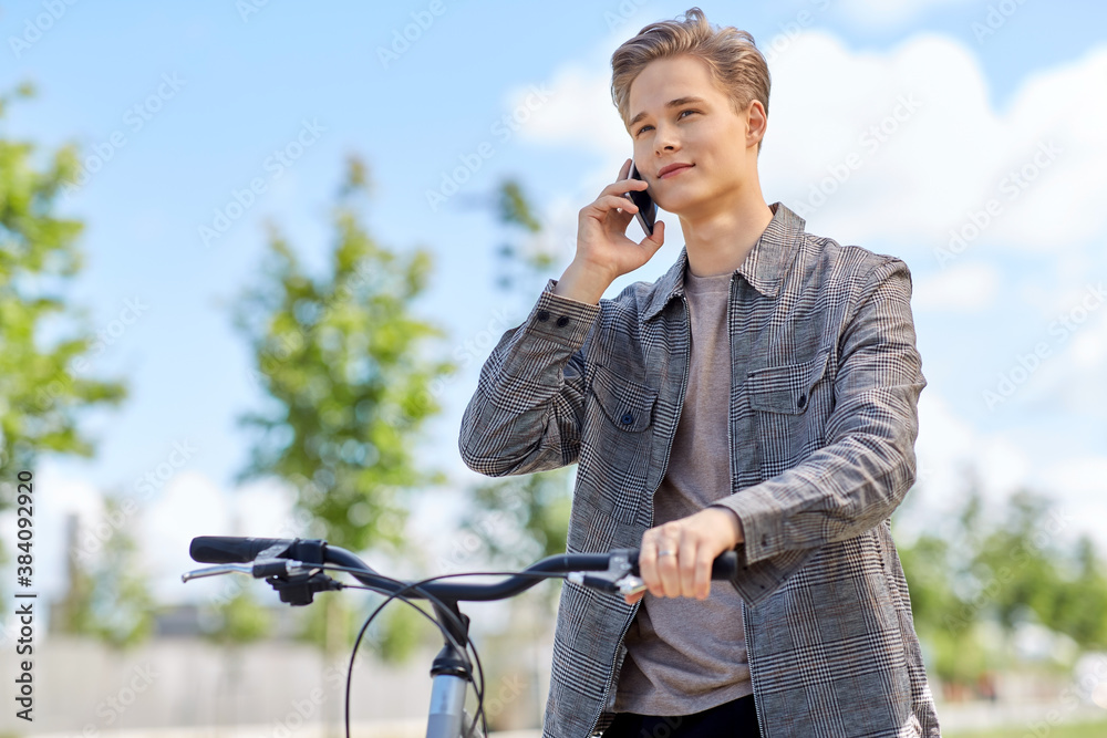 Fototapeta premium lifestyle, transport and people concept - young man or teenage boy with bicycle calling on smartphone in city
