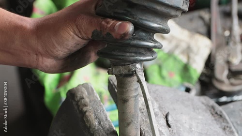 Hand of Car Mechanic or Auto Mechanic Removing Drive Shaft Rubber Boot Band in Zoom View
