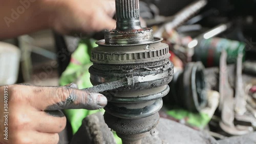 Car Mechanic or Auto Mechanic Removing Outer Drive Shaft Rubber Boot Band in Zoom View