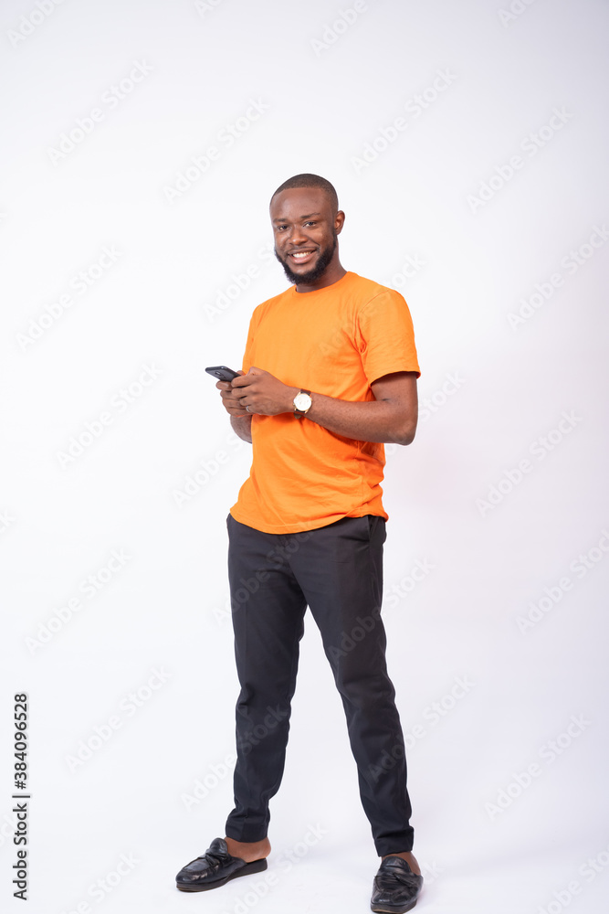young man holding his phone smiling, standing on a white background, texting concept young man holding his phone smiling, standing on a white background, texting concept