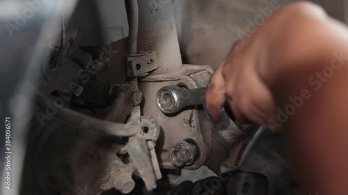 Car Mechanic or Auto Mechanic Tighten Bolt and Nut of Shock Absorber by Wind Block in Zoom View
