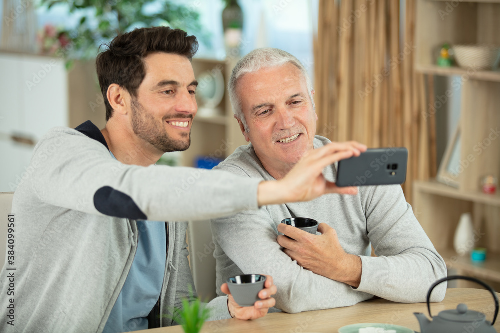 Fototapeta premium mature man taking selfie with his son at home