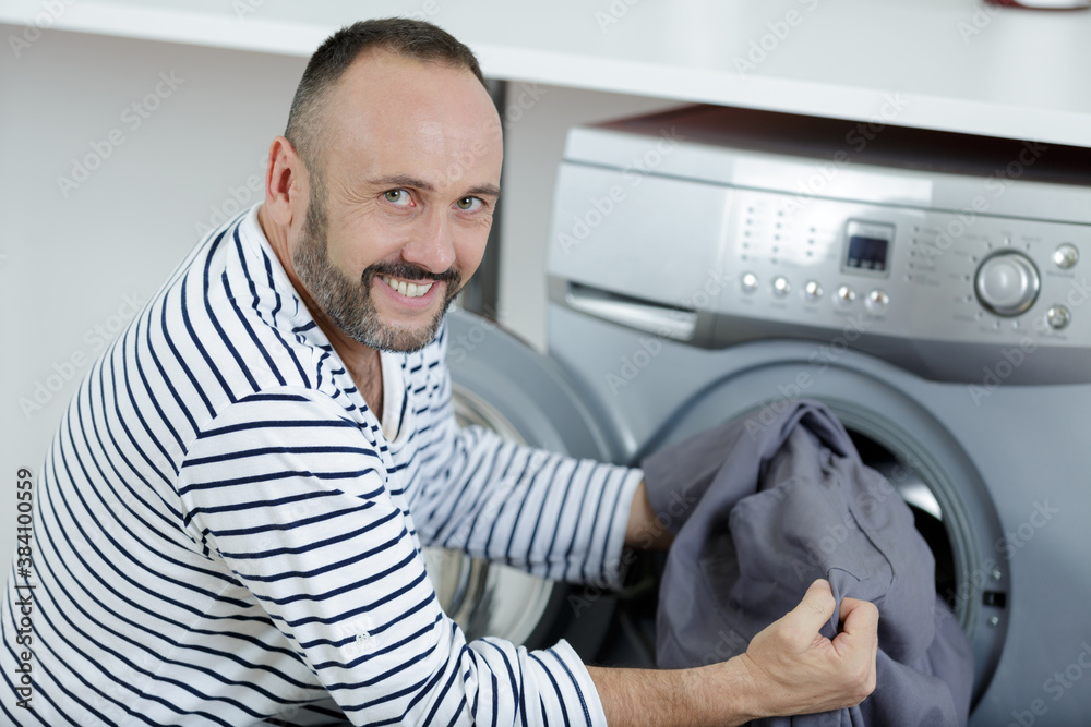 Obraz premium man loading clothes into washing machine