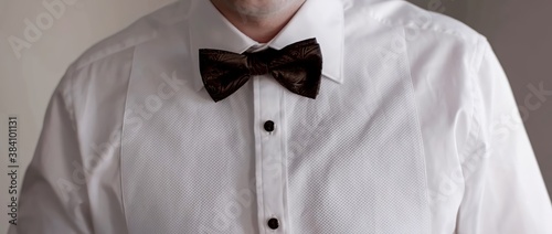 Photo Man in a white shirt with black glossy buttons and a black bow tie