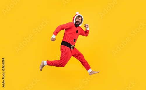 happy bearded male in red santa claus costume running and feel happiness about christmas shopping sales, new year holiday