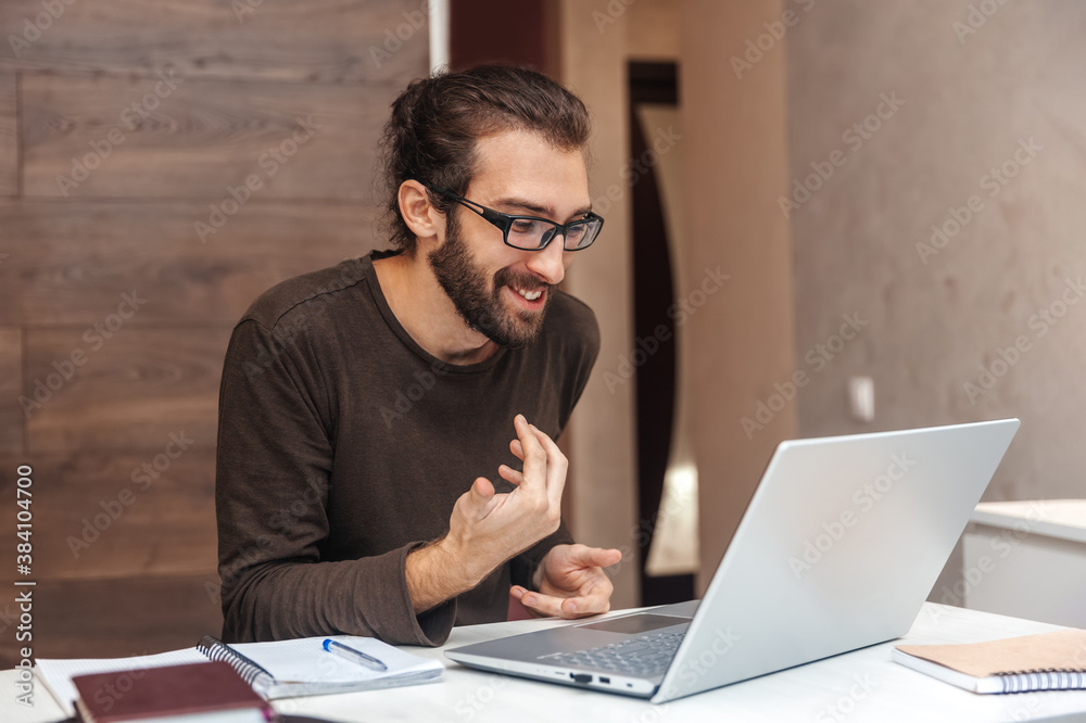 Positive man talking on video link using laptop while sitting at home during quarantine Positive man talking on video link using laptop while sitting at home during quarantine