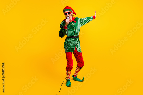 Full length body size view of his he nice attractive cheerful popular talented funny guy elf singing hit having fun Eve Noel isolated over bright vivid shine vibrant yellow color background
