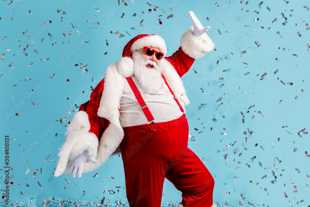 Photo of pensioner old man grey beard careless north pole closed party dance having fun colorful confetti wear santa x-mas costume suspender sunglass cap isolated blue color background - obrazy, fototapety, plakaty 