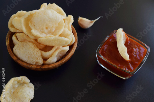 Fresh made Prawn Crackers (Krupuk)  on dark background.Prawn Crackers or Shrimp Chips with ketchup and garlic. photo