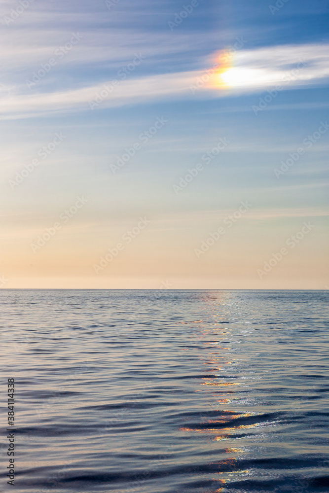 Halo with sun dog and colorful reflections in the sea