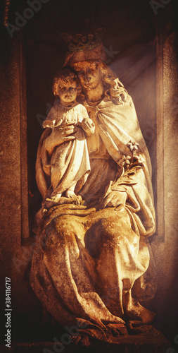 Ancient statue of Queen of Heaven Virgin Mary with Jesus Christ in sunlight. Religion, faith, love, Christianity concept.