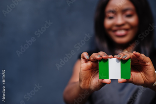 Quadro su tela African woman hold small Nigeria flag in hands.