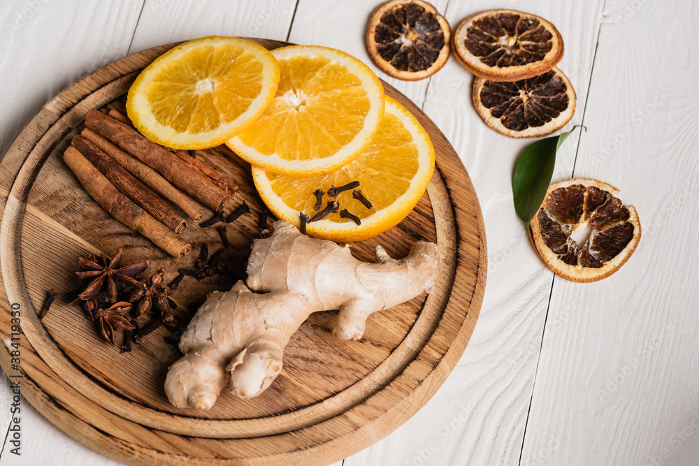 Wooden plate with spices, ginger root and orange slices on wooden background Wooden plate with spices, ginger root and orange slices on wooden background