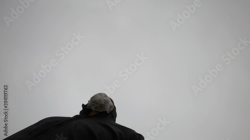 vista desde abajo de un hombre corriendo con su mameluco y su mascarilla en un dia nublado photo