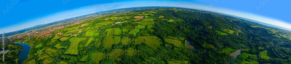 Aerial panoramic view of over green hilly landscape with small town