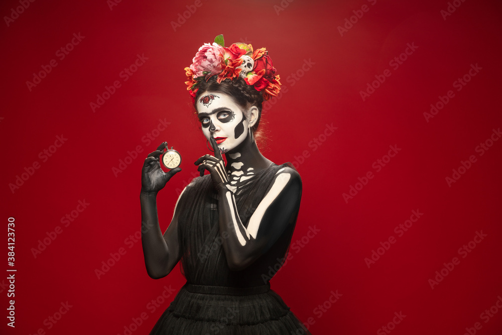 Hurry up. Young girl like Santa Muerte Saint death or Sugar skull with bright make-up. Portrait isolated on red studio background with copyspace. Celebrating Halloween or Day of the dead. Sales Hurry up. Young girl like Santa Muerte Saint death or Sugar skull with bright make-up. Portrait isolated on red studio background with copyspace. Celebrating Halloween or Day of the dead. Sales