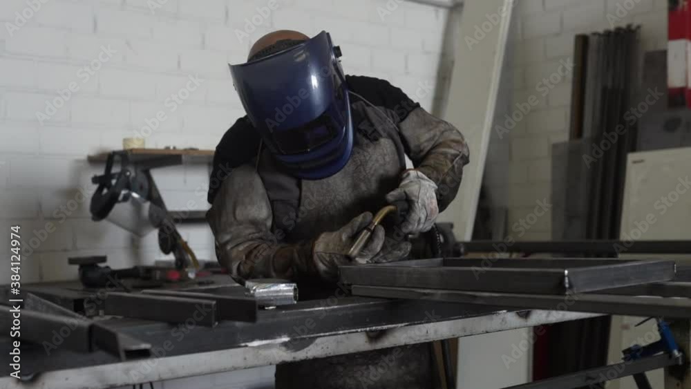 Professional welder in protective helmet in workshop Professional welder in protective helmet in workshop