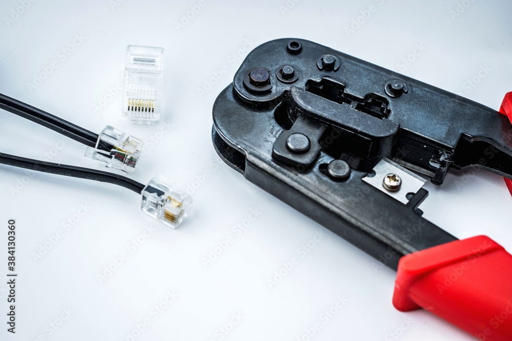 Crimping tool with red handle isolated on white background and RJ-45 connector. Crimping tool with red handle isolated on white background and RJ-45 connector.