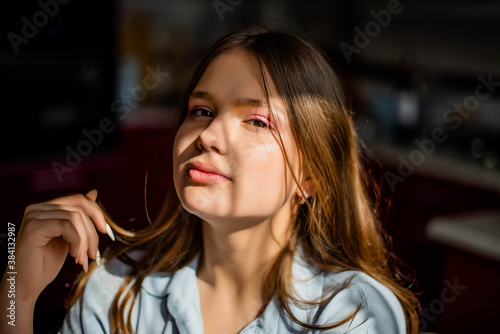 Fashion lifestyle image of pretty teenage young woman sitting in kitchen.