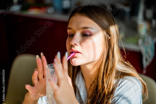 Fashion lifestyle image of pretty teenage young woman sitting in kitchen.