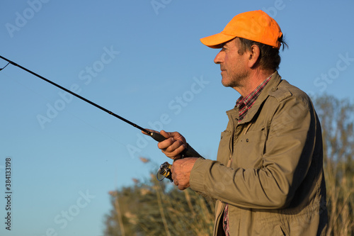Fishing rod wheel closeup, man fishing with a beautiful sunset.