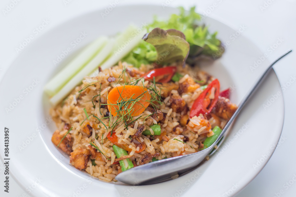 Fried eice with salted egg and cracklings served on a white plate.