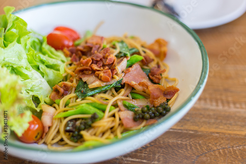  Organic chinese  kale and crispy bacon spaghetti on a wooden table.