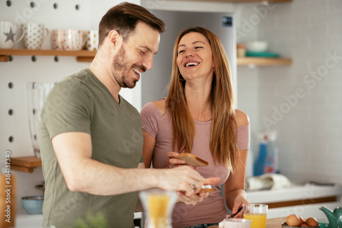 Young couple making breakfast at home. Loving couple eating sandwich in kitchen.